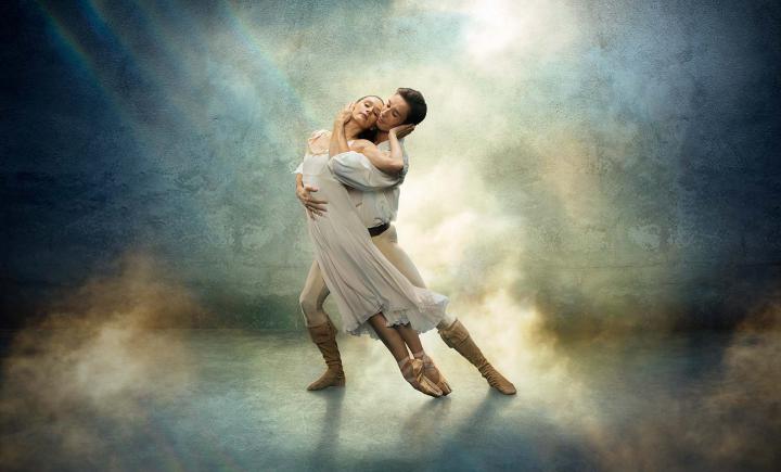 Star-crossed lovers Romeo & Juliet in a loving embrace, both wearing white against a fantasy blue and yellow background.