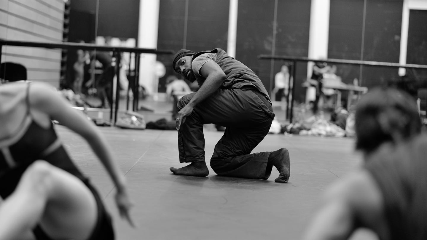 Dickson Mbi kneeling on the the studio floor barefoot