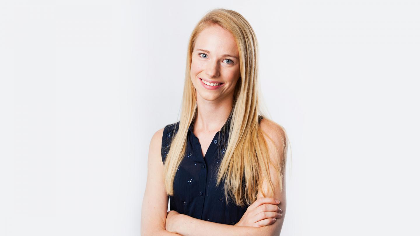 Isabelle Clough smiling directly to the camera dressed in a dark blue top against a white backdrop.