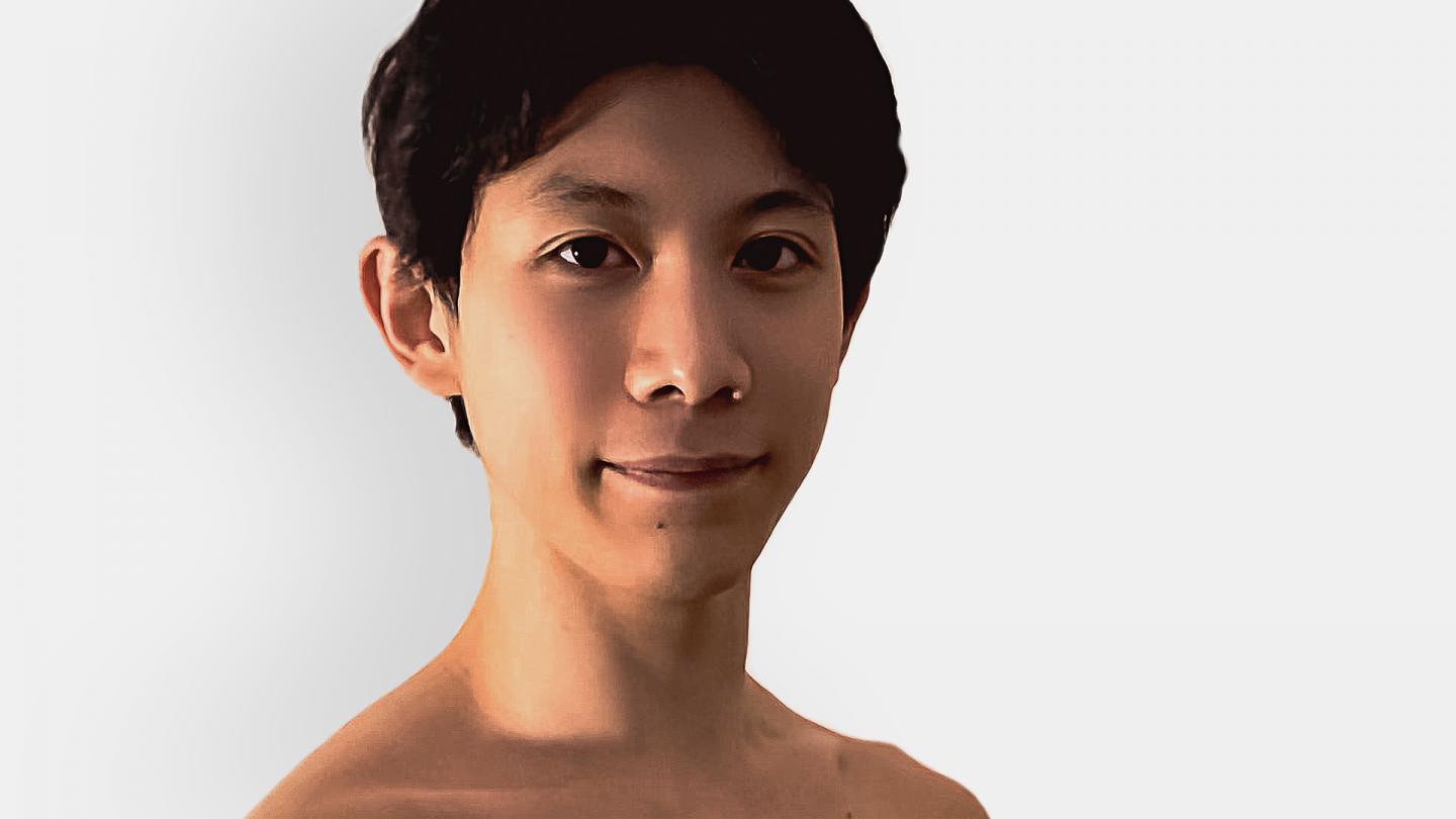 Male dancer with dark hair looking straight at the camera smiling