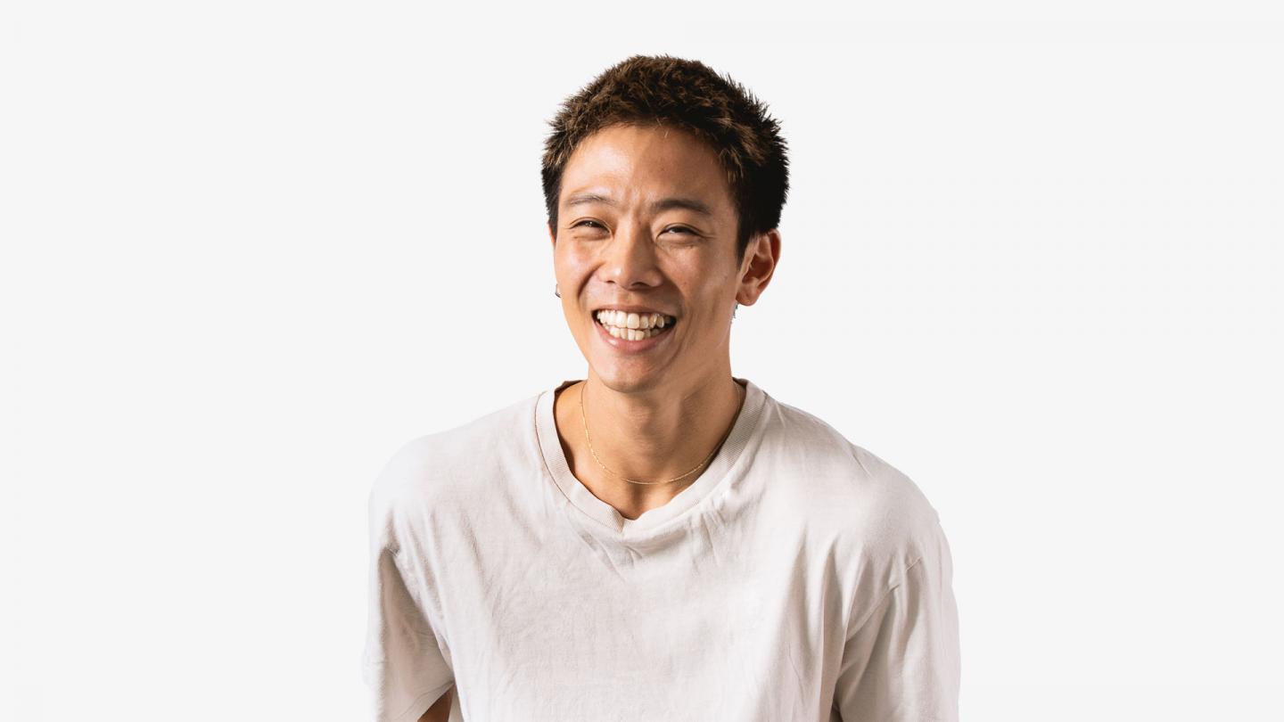 A headshot of a man laughing in a white t shirt