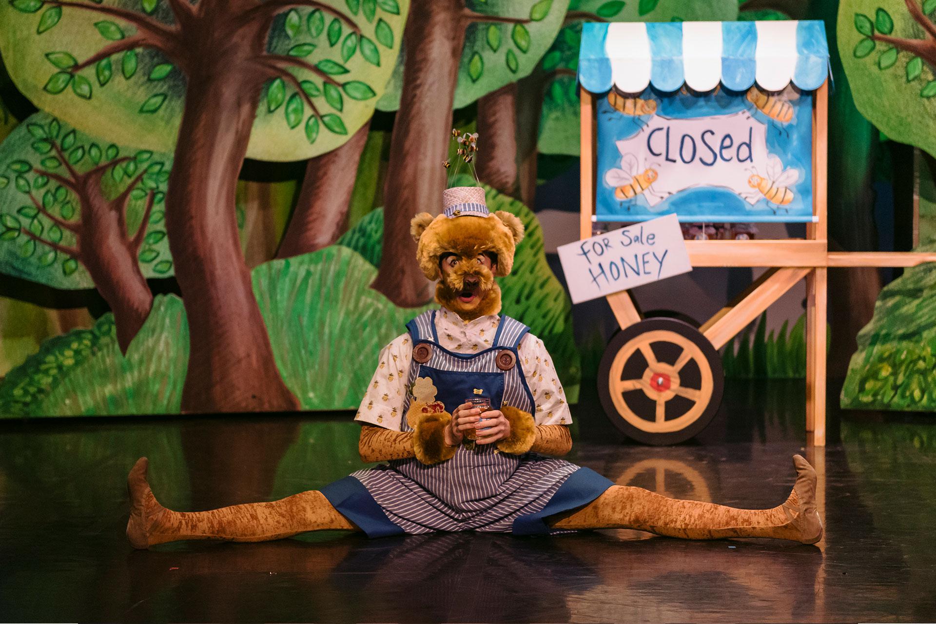 Little Red Riding Hood, production, 2019, Matthew Morrell as Bear, photo Drew Forsyth Bear rests after he has sold all the honey from his stall