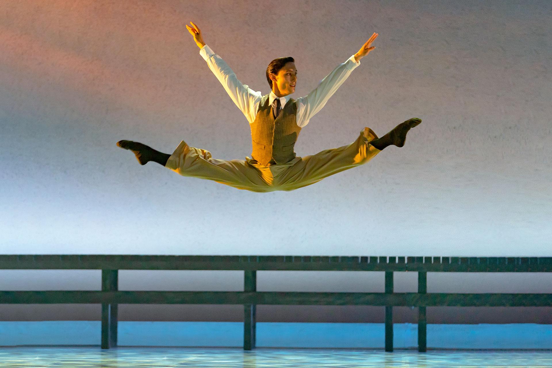 Kevin Poeung as Nick Carraway leaping with his legs in splits in The Great Gatsby. Photo Emma Kauldhar
