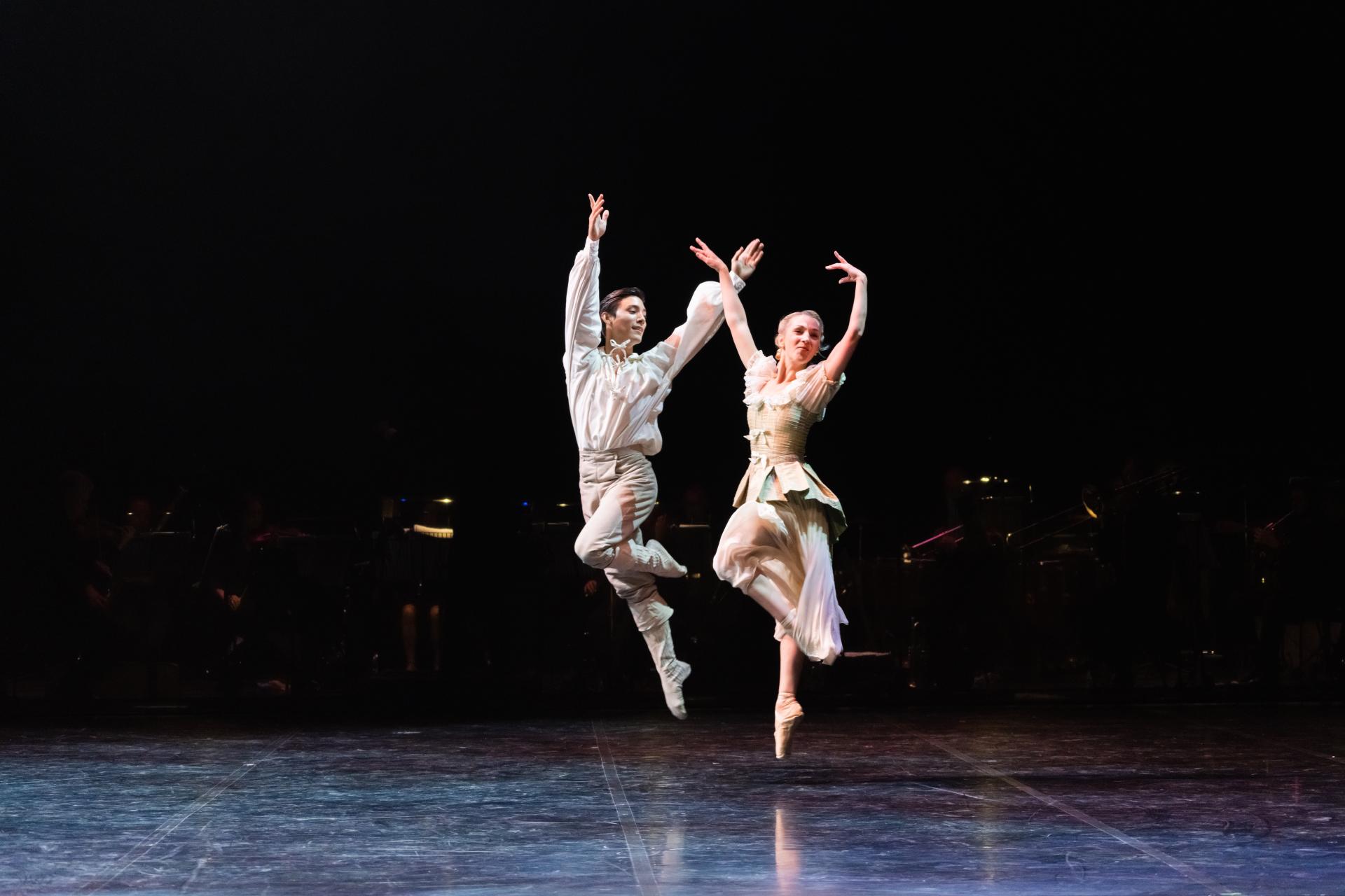 Two dancers leap in the hair, arms aloft