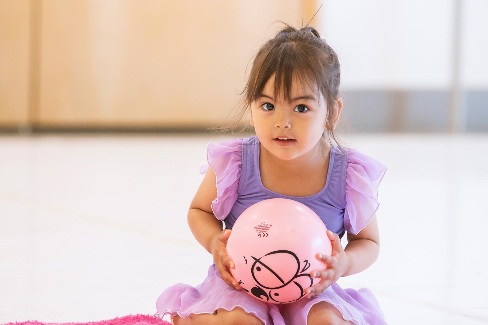 Little girl in purple dress holding a ball