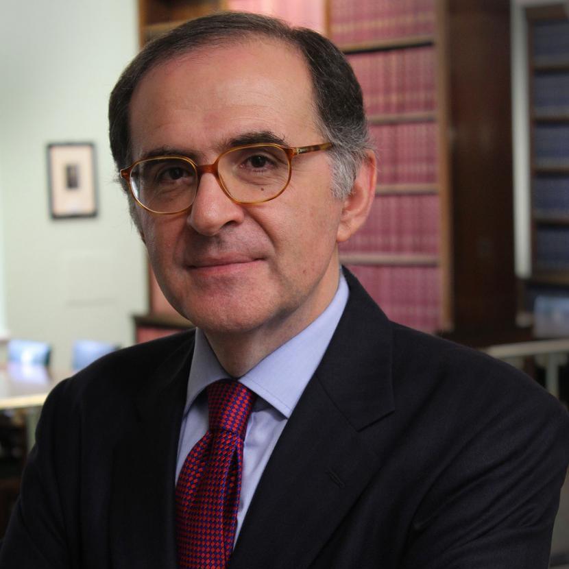 Guy Perricone wearing a red tie, blue shirt, a jacket and glasses.