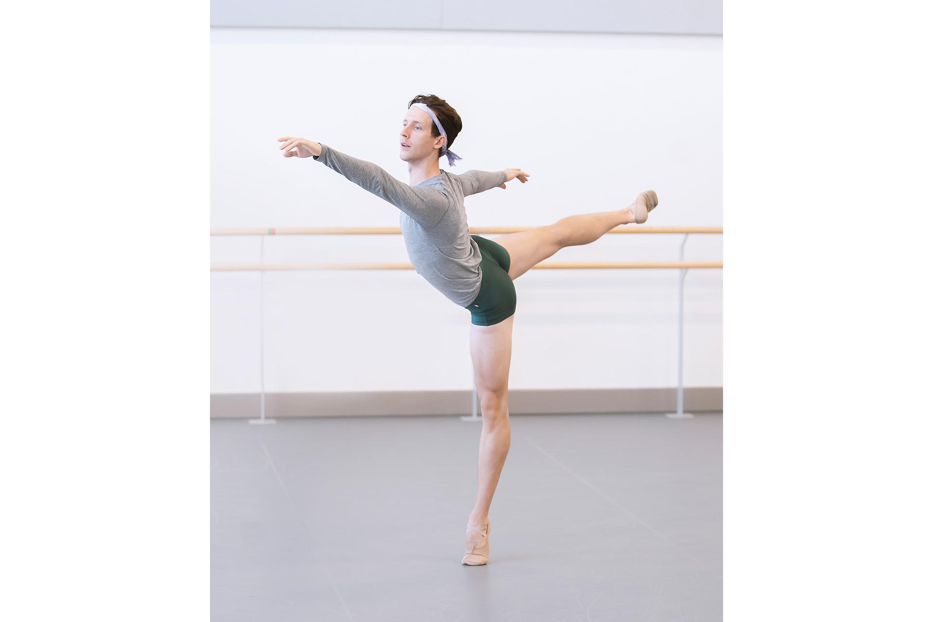 Male dancer in arabesque, one arm in front and another behind him as he rehearses