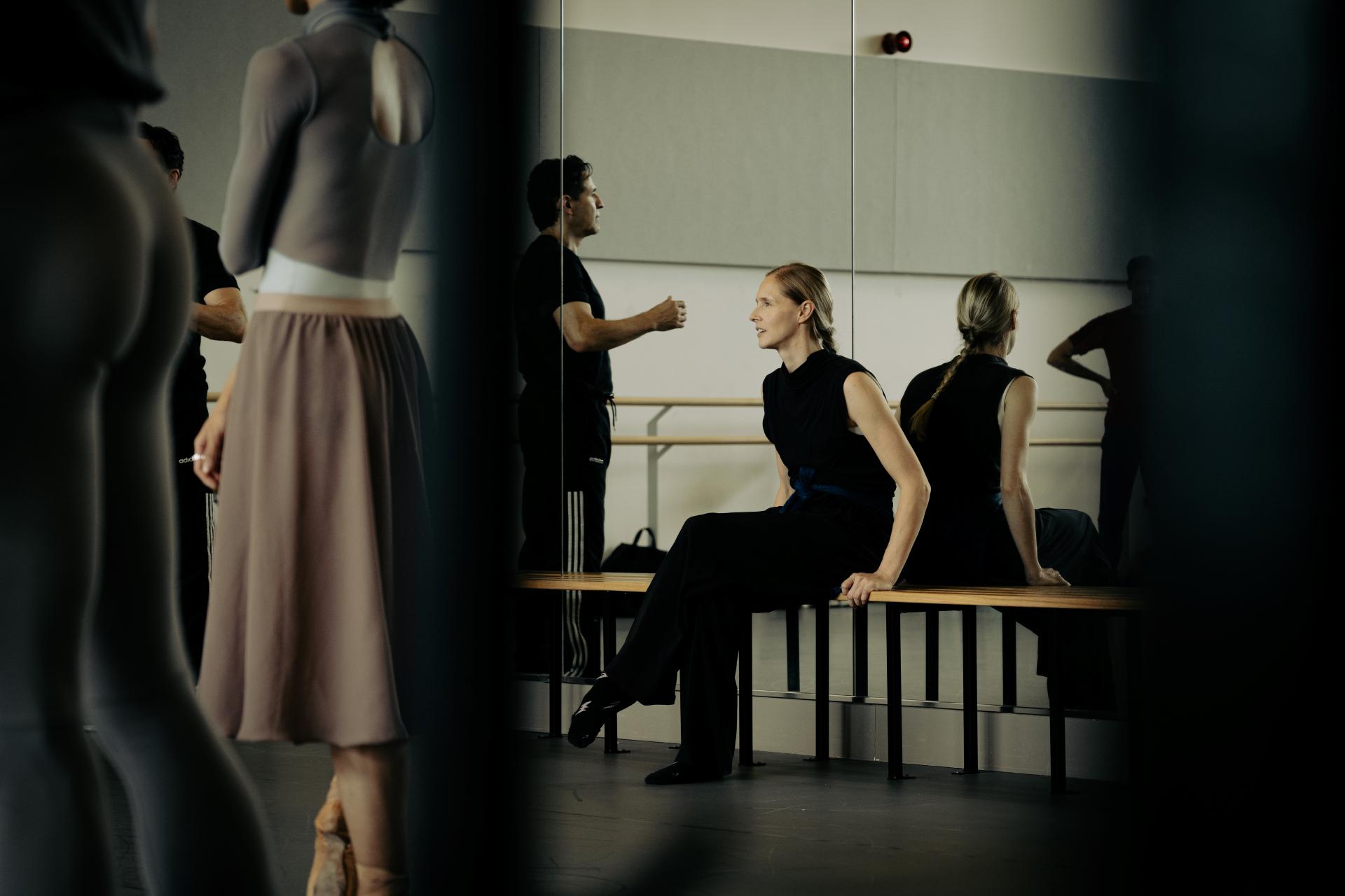 Stina Quagebeur sits on a bench watching a rehearsal