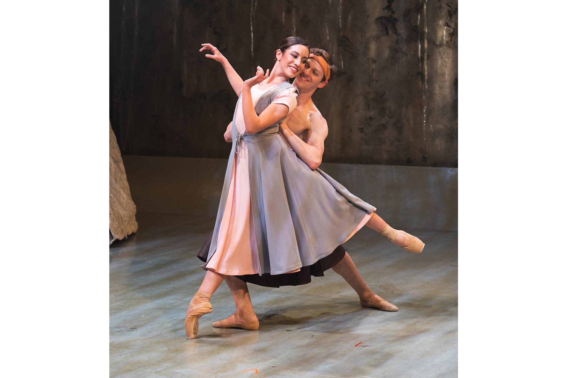 Woman standing in one foot leaning back while supported by a smiling dancer holding her back