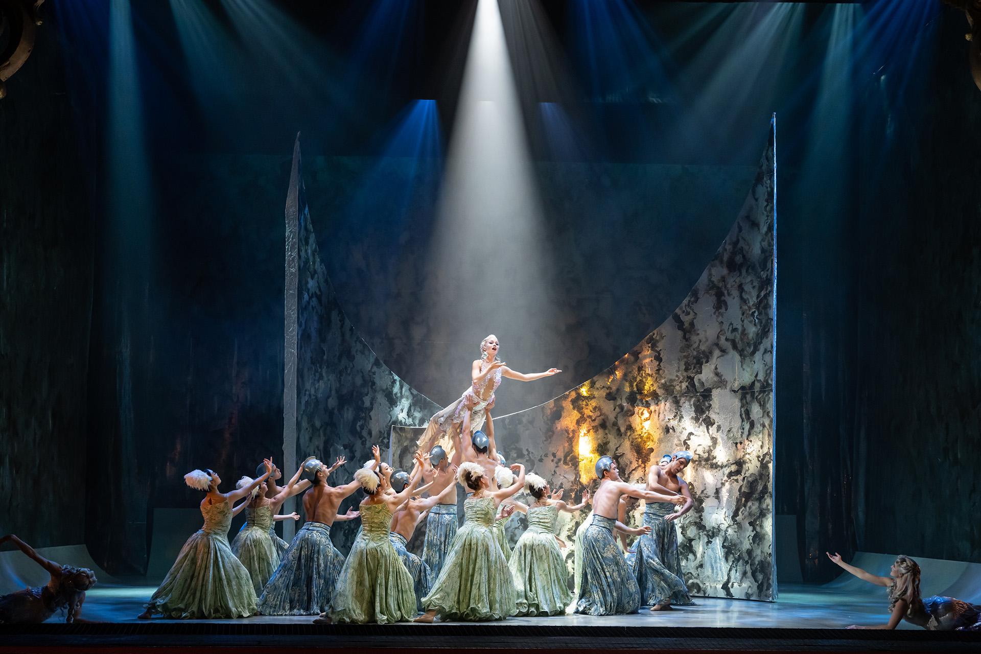 The Little Mermaid, production, 2022, Abigail Prudames and Northern Ballet dancers. Photo Bill Cooper Dancers in skirts of blue and green representing the sea, support MArilla, light shining on her from above and singing