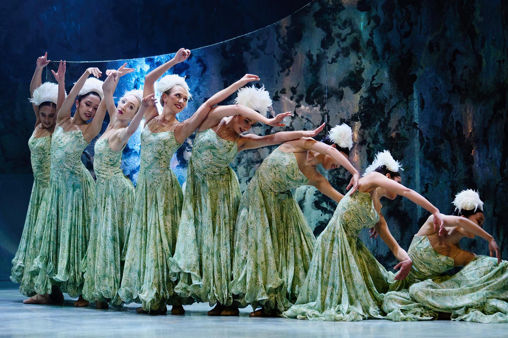 The Little Mermaid, production, 2022, Northern Ballet dancers. Photo Kyle Baines Female dancers wearing green dresses and white hats reaching up and gradually kneeling down.