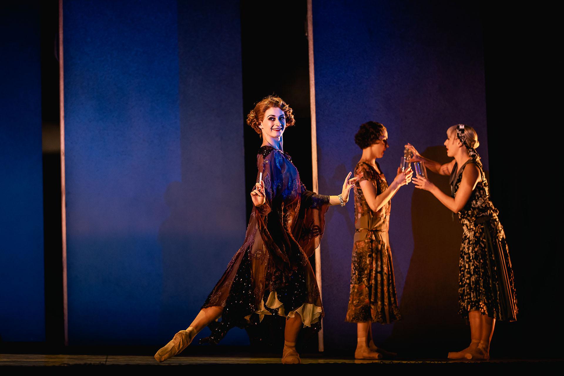 The Great Gatsby, production, 2023, dancer Amber Lewis. Photo Emily Nuttall Dancer in a burgundy 20s-style dress stands with her hands in a classic flapper pose