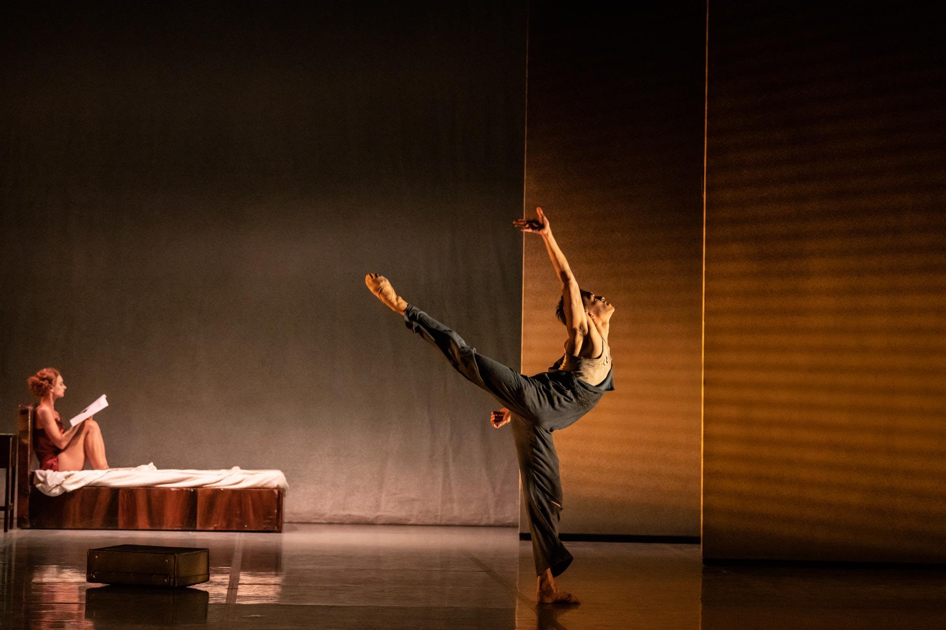 A male dancer reaching backwards with one leg raised