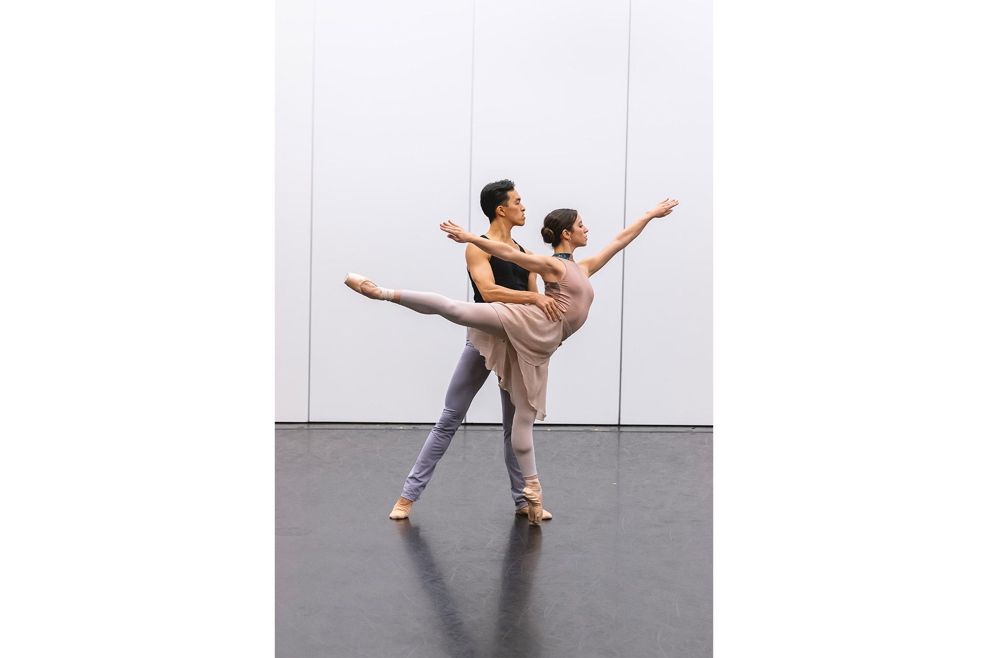 Female dancer in arabesque while a male supports her by holding her waist