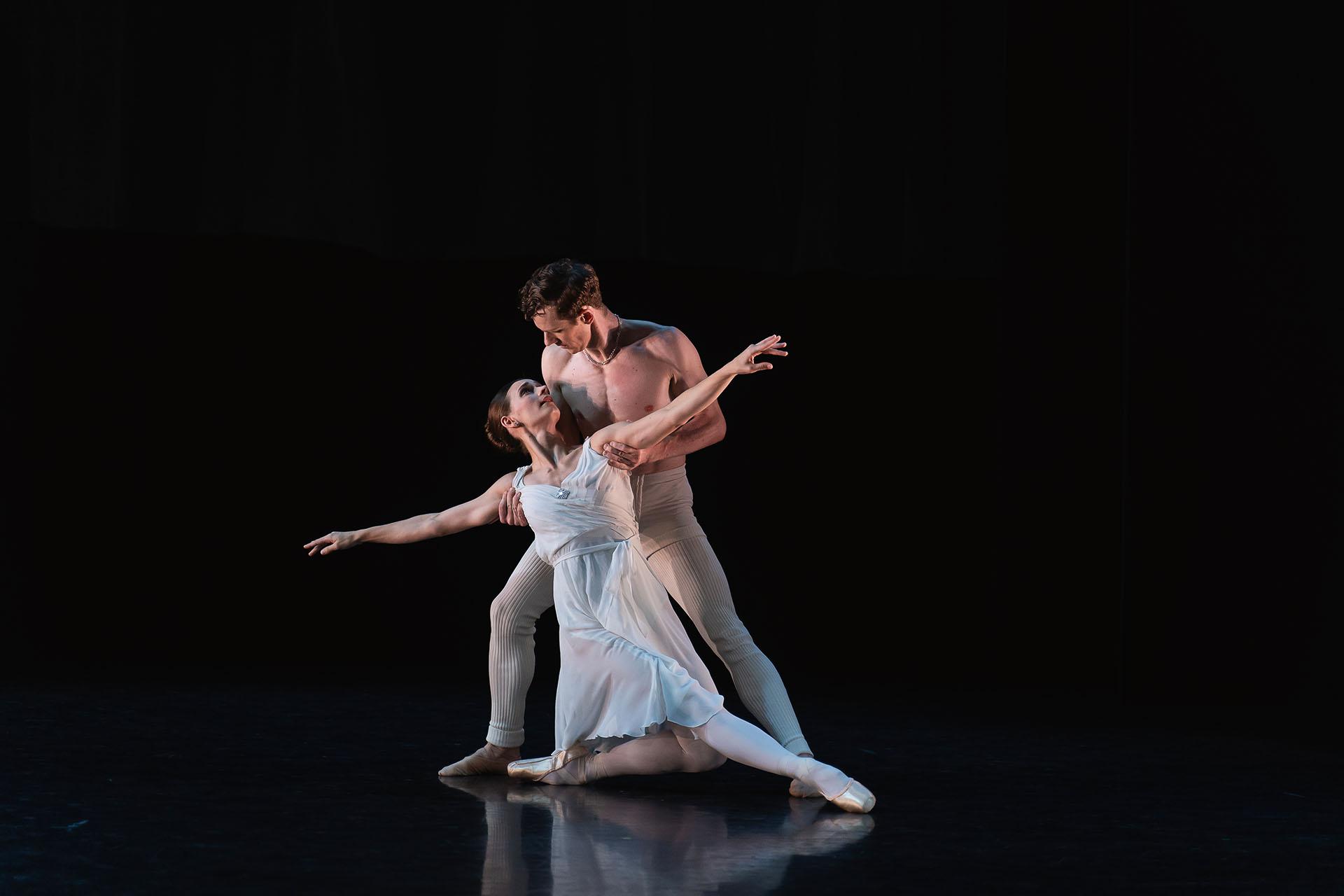 Generations, 2023, production, Amber Lewis and Jonathan Hanks in Adagio Hammerklavier. Photos Emily Nuttall Dancers in white, one standing and holding the other by their arms as they are close to the ground, on knee bent and the other leg stretched out front