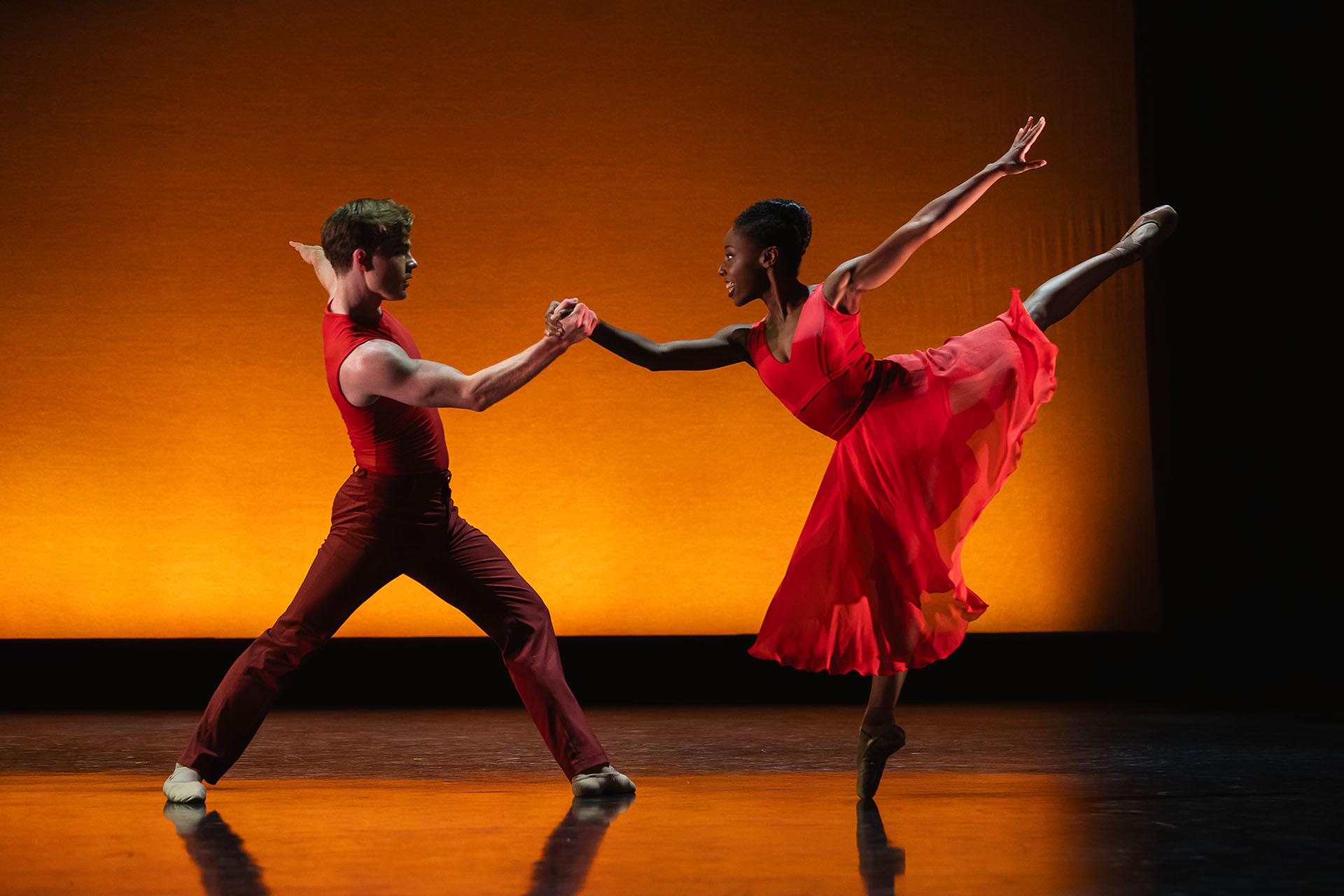 Generations, 2023, production, Harris Beattie and Aerys Merrill in Intimate Pages. Photos Emily Nuttall Woman balances en pointe on one foot, leg behind her raised high and another dancer helping her balance by holding her right hand