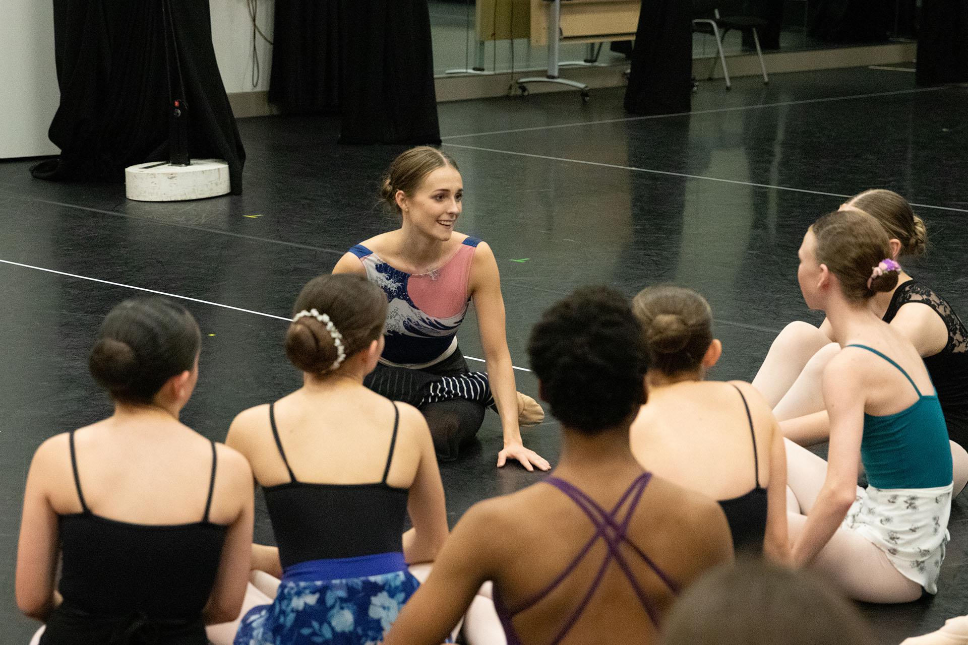 Dancer sat down talking to ballet students
