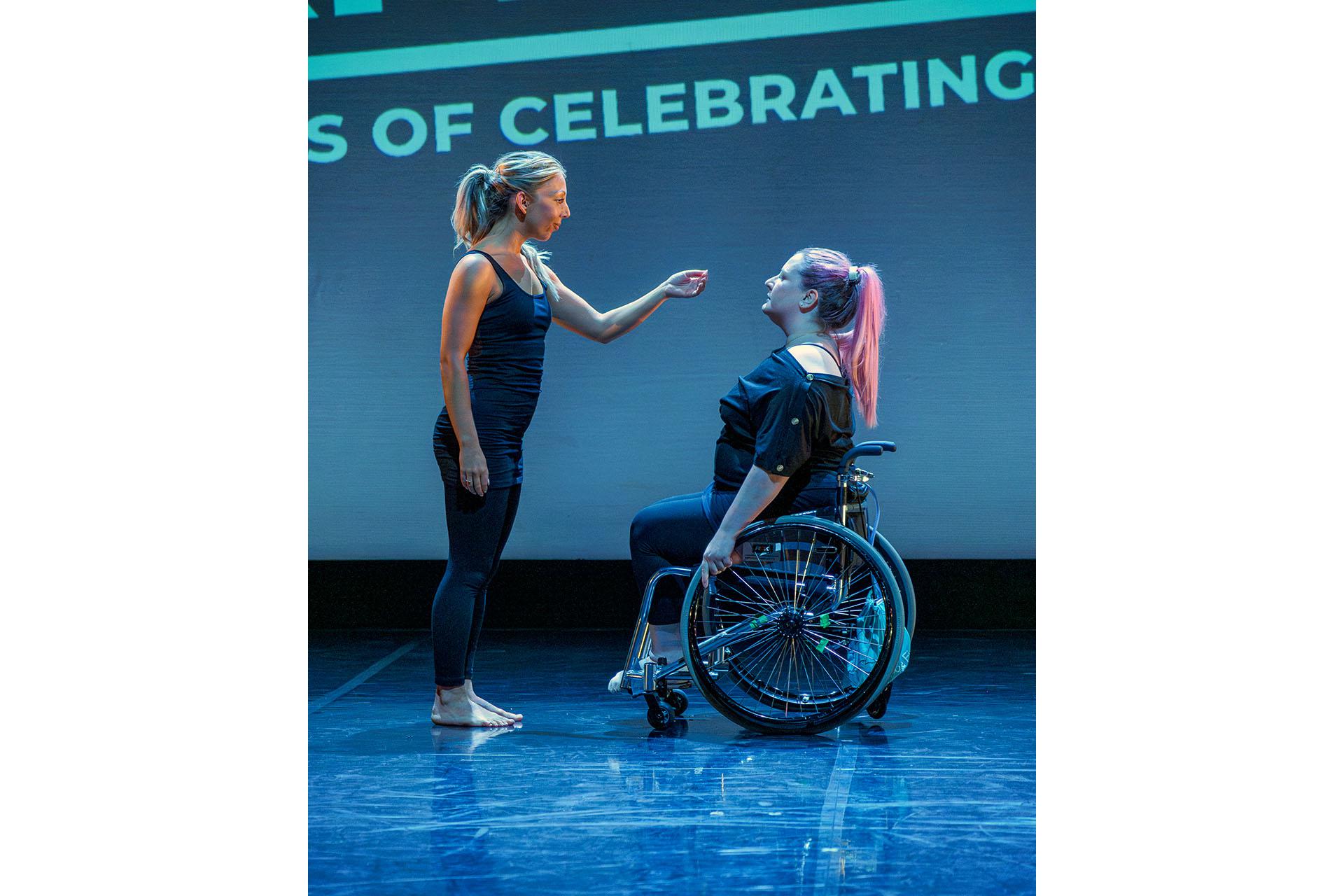 Woman in a wheelchair looks at another woman stood in front of her