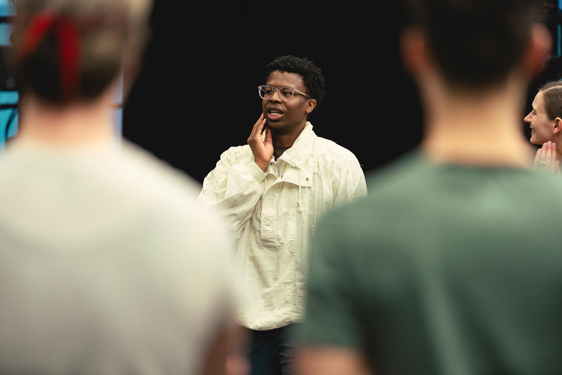 Choreographer Mthuthuzeli November in a white shirt strokes his chin as he gives instructions