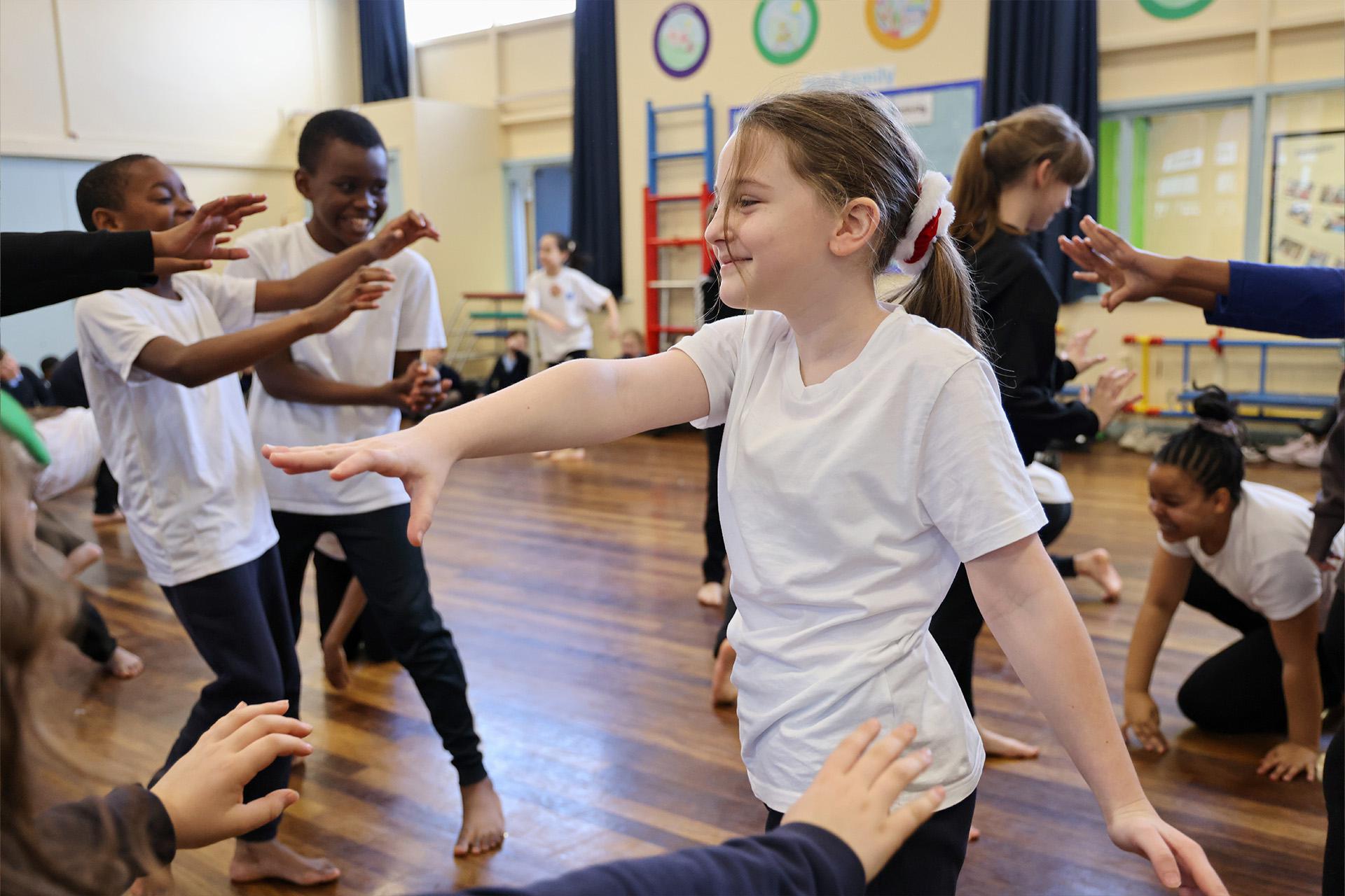 Girl in a white T-shirt and her hair tied in a pony tail, participating in dance