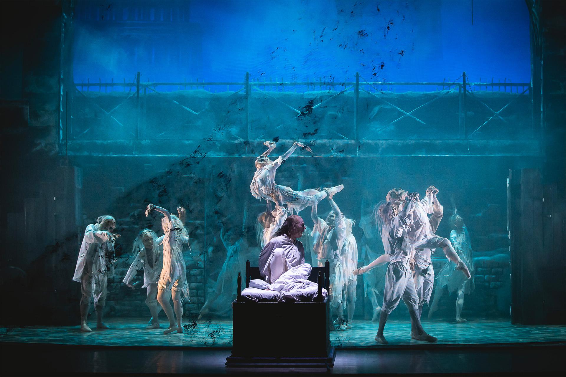 A Christmas Carol, 2024, production, Northern Ballet dancers, photo Emily Nuttall Scrooges sits up in his bed as wraiths dance behind him