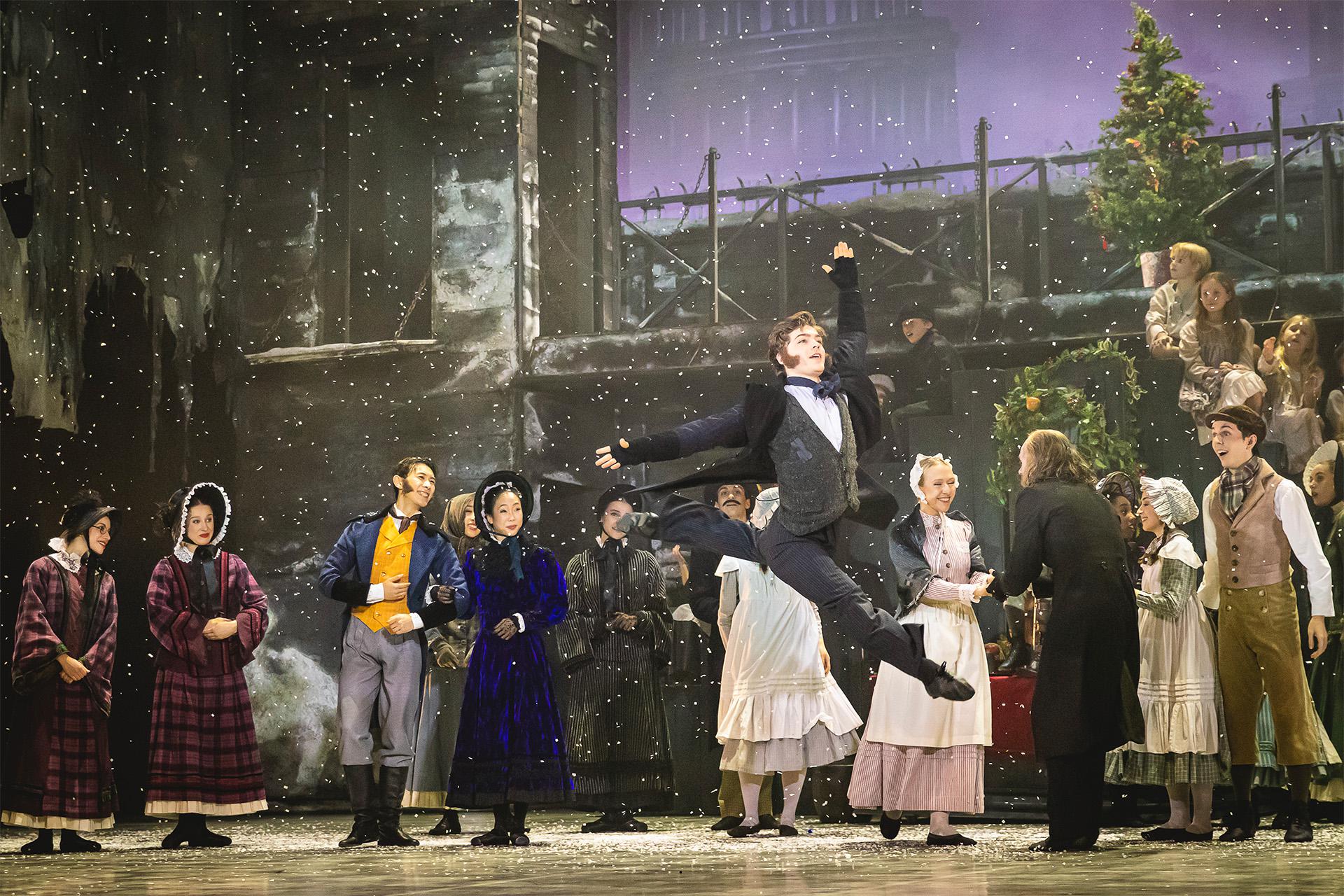 A Christmas Carol, 2024, production, dancer Harris Beattie, photo Colleen Mair Bob Cratchit leaps into the air as snow falls and townspeople watch on in delight