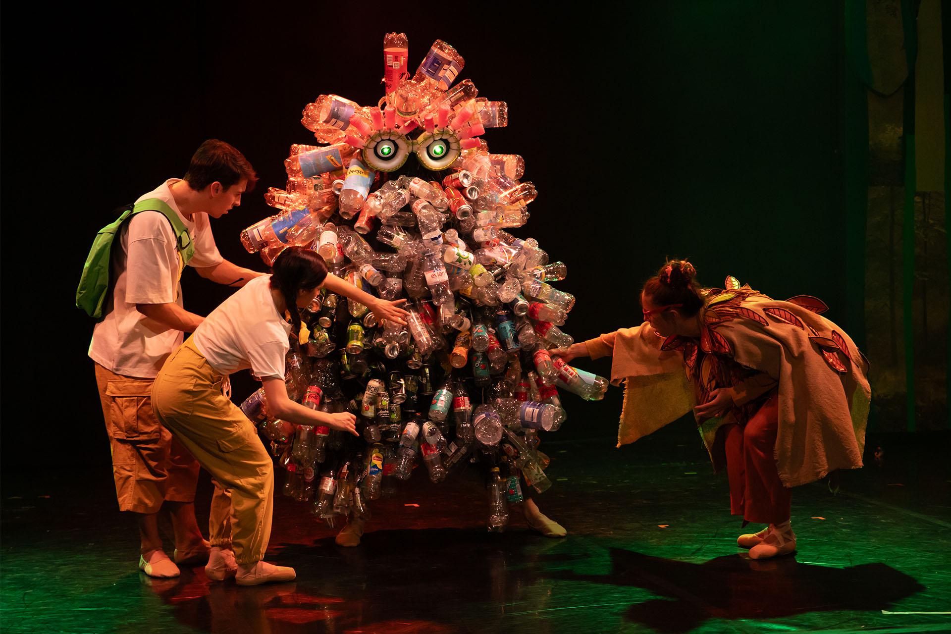 Hansel, Gretel and the Lady of the Forest look at the plastic bottles and cans on the Rubbish Monster.