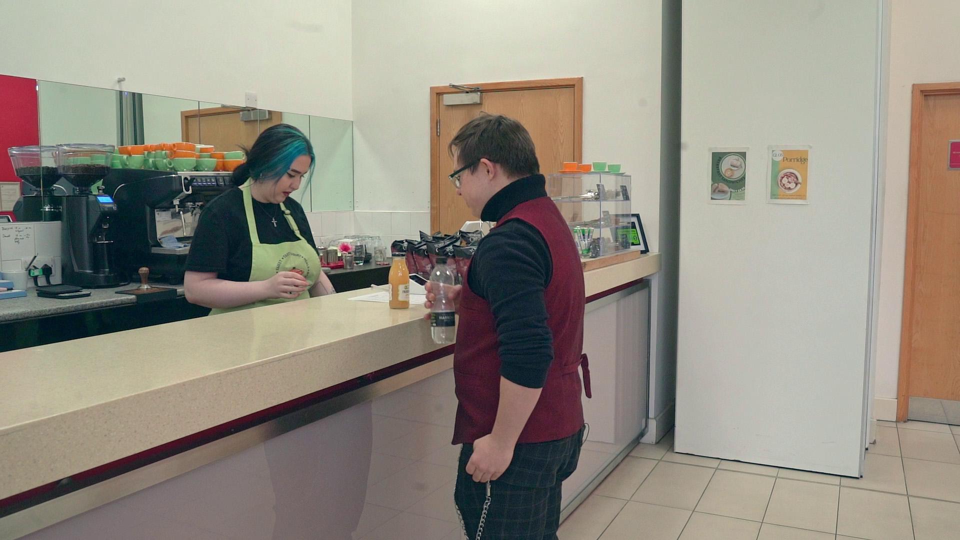 Two people at the cafe bar, one person serving the other