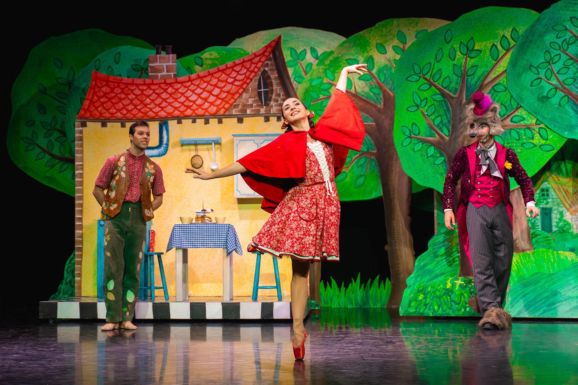 Little Red Riding Hood, production, 2025, dancer Julie Nunès. Photo Emily Nuttall In front of her house and with her father and the wold looking on, Little Red in her bright red shawl and vibrant red pointe shoes dances and smiles