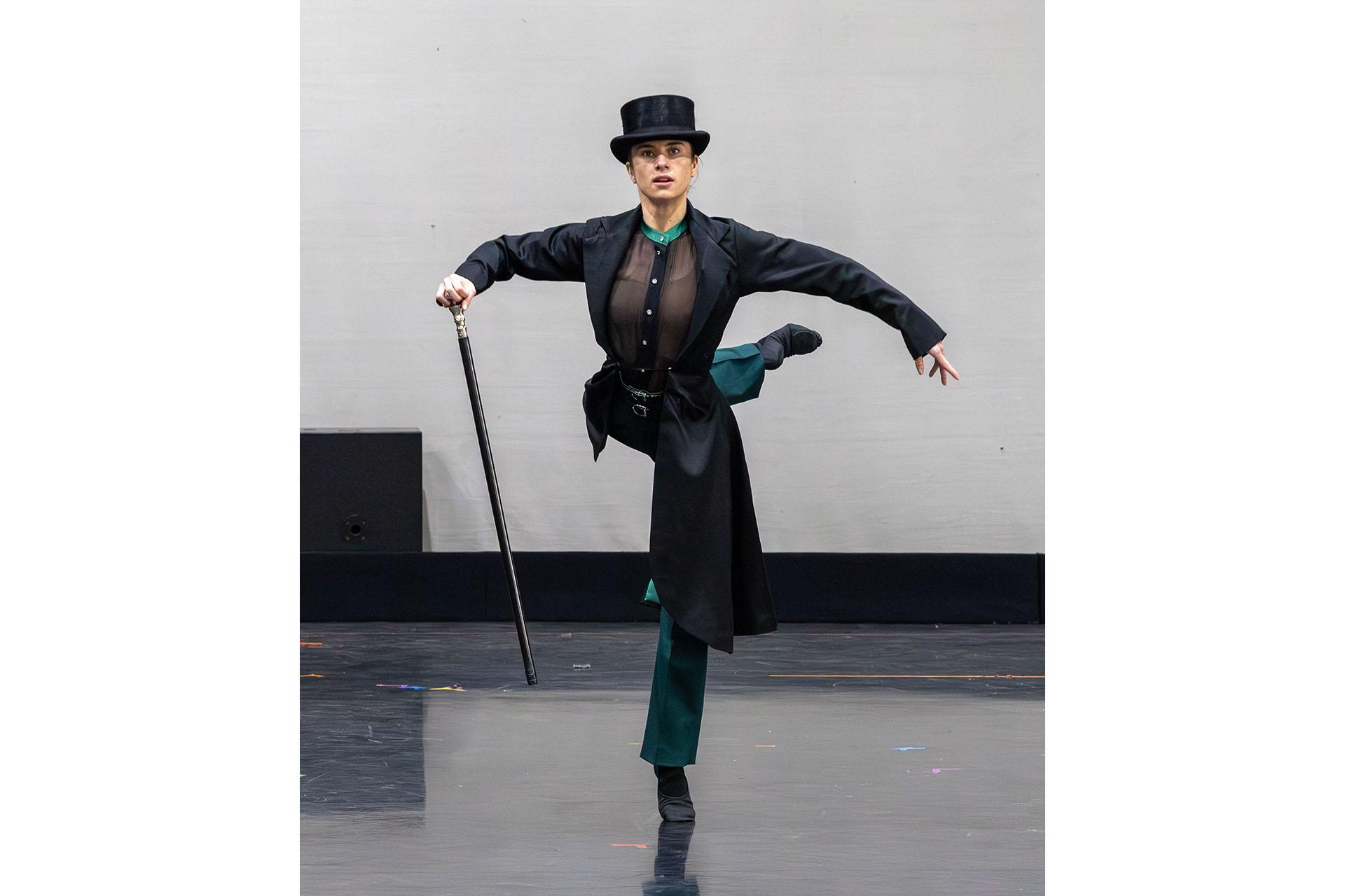 Woman in tall hat, long black cane and carrying a silver topped cane