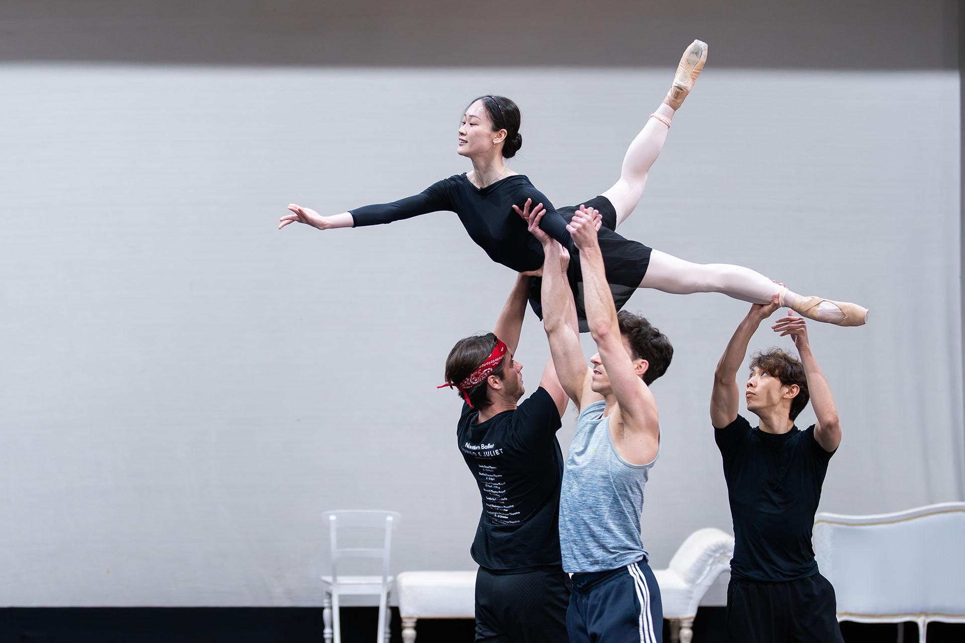 Three dancers holding a fourth aloft