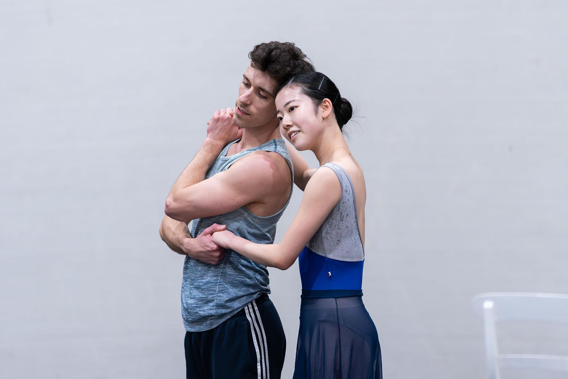 Two dancers, each with dark hair, hold one another