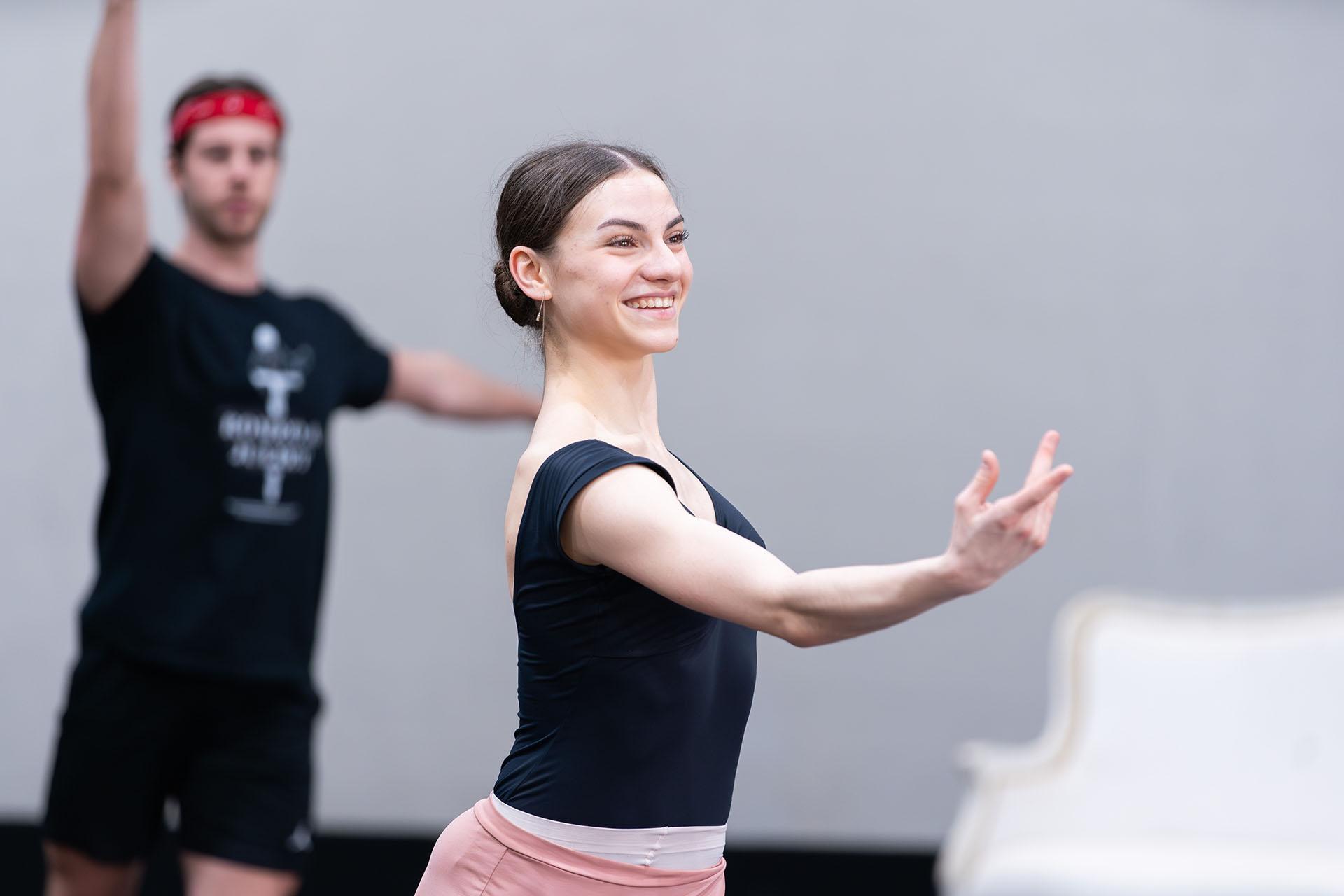 Dancer in the rehearsal room, dark hair tied tightly back, dark leotard top