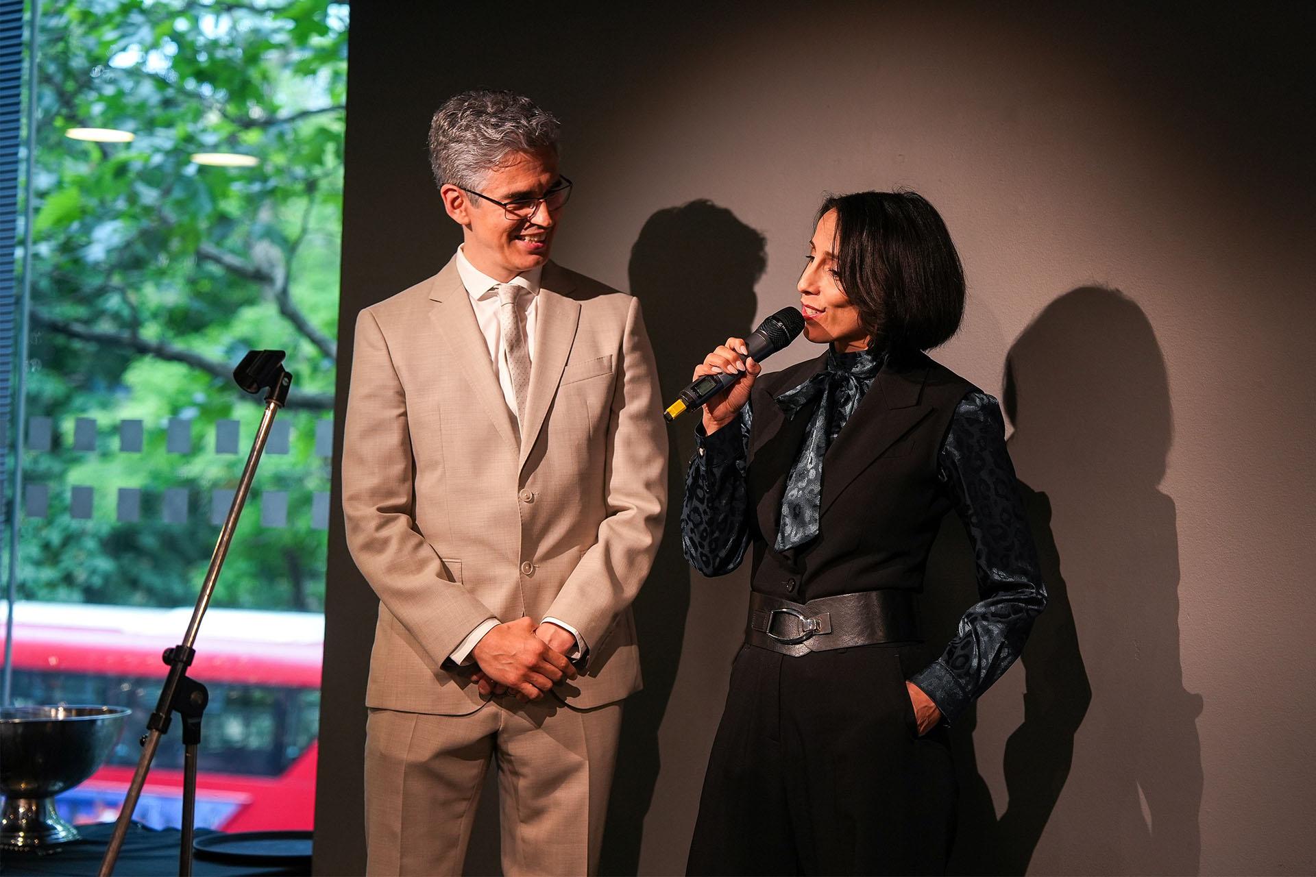 Gentleman Jack choreographer, Annabelle Lopez Ochoa, speaking into a hand-held microphone while Northern Ballet Artistic Director, Federico Bonelli, smiles next to her