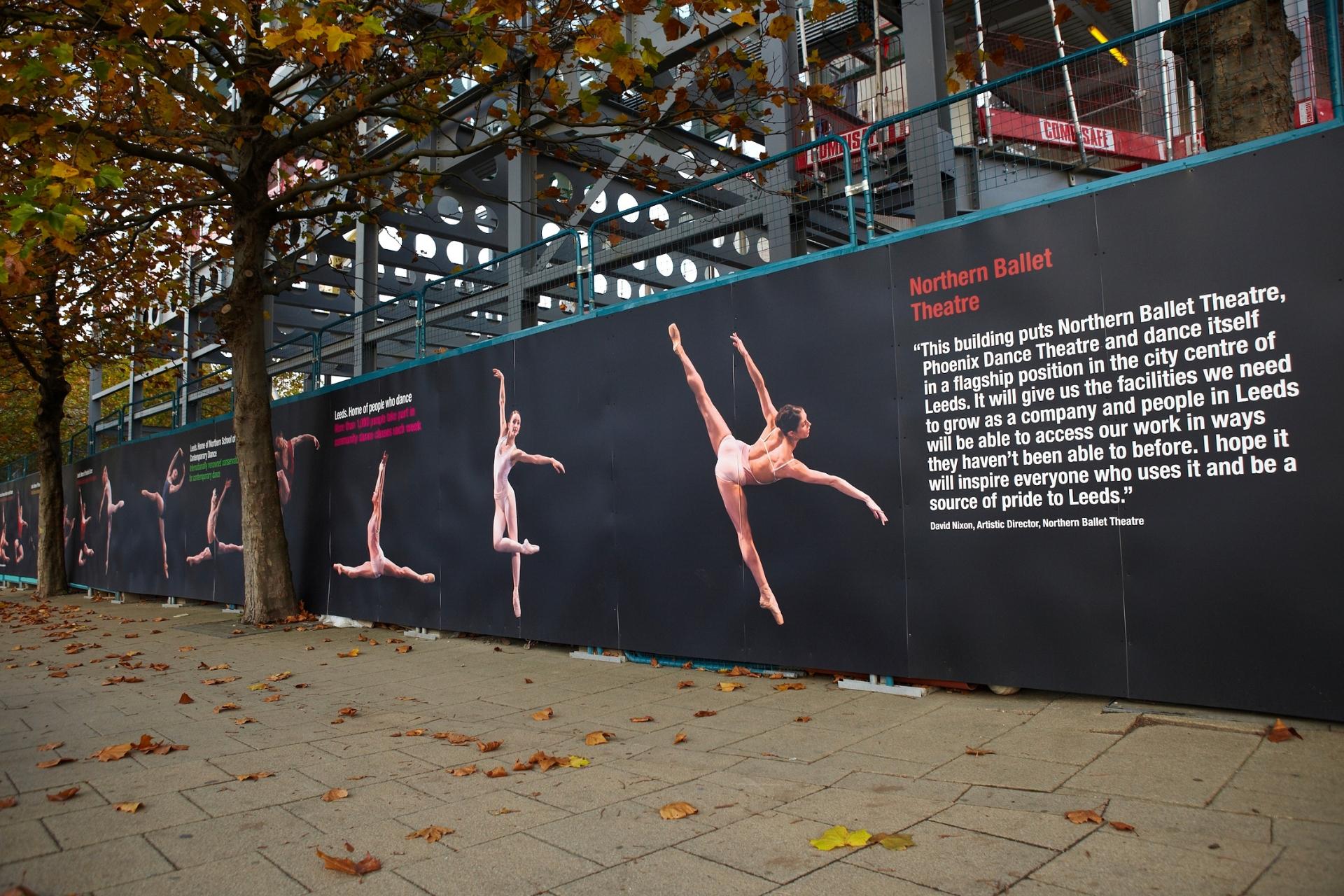 A large banner outside a construction sight featuring images of various ballet dancers.