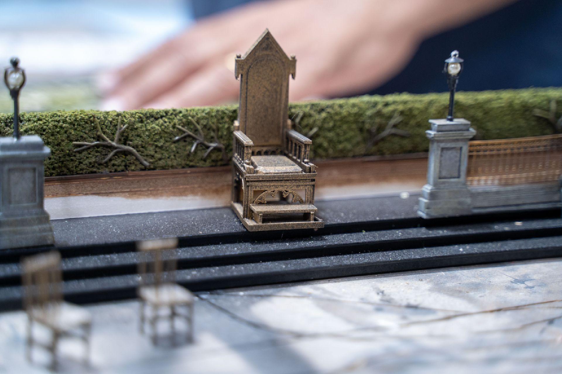 A diorama of the Court set of Swan Lake, featuring a large throne in front of some green hedges.