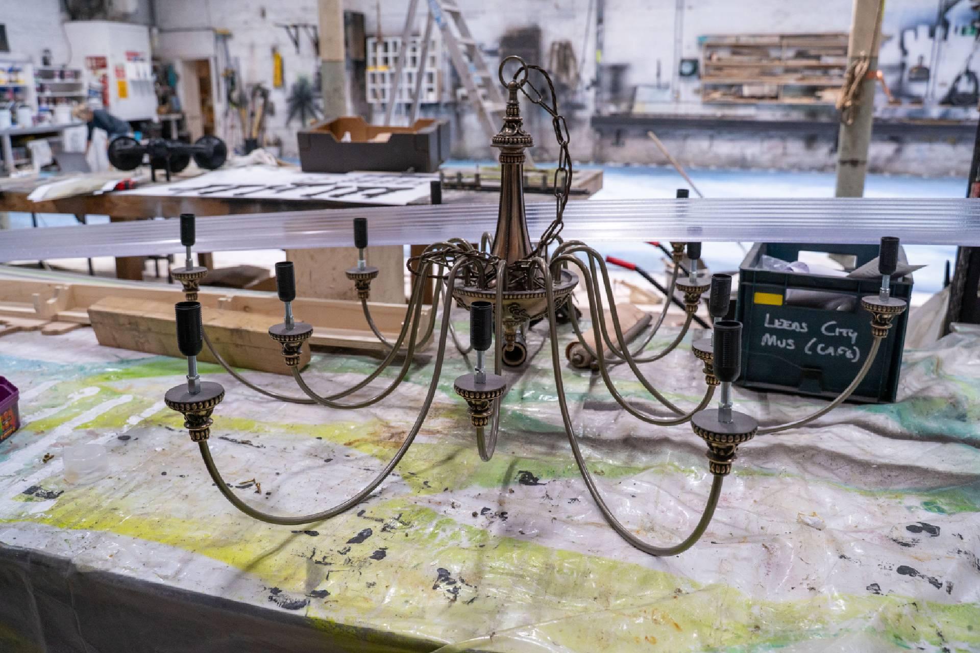 A large metal chandelier sat atop a workshop table.