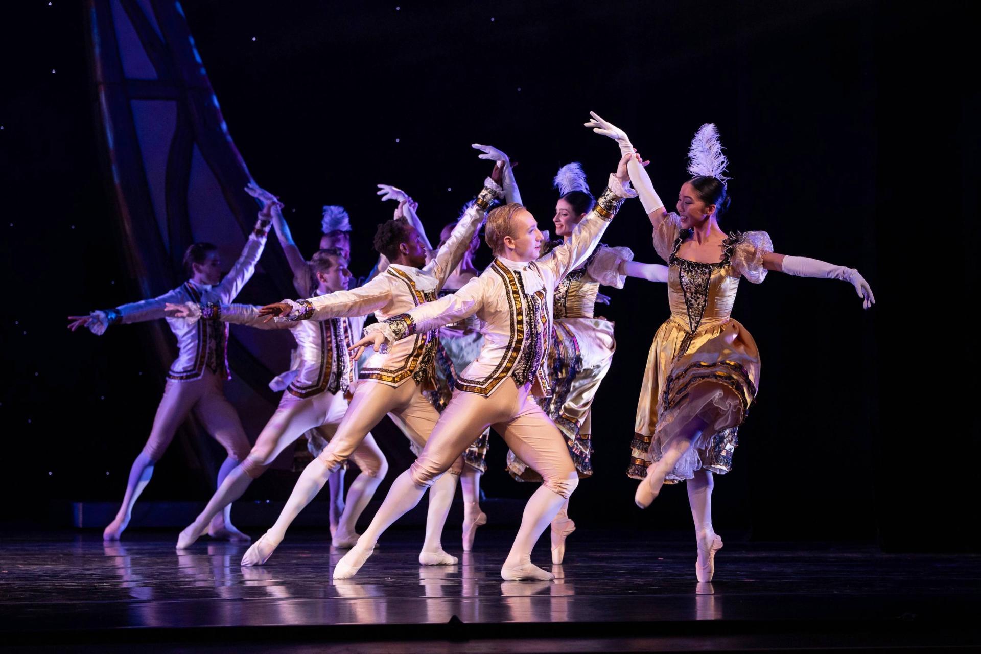 A group of company dancers are partnered and they dance together.