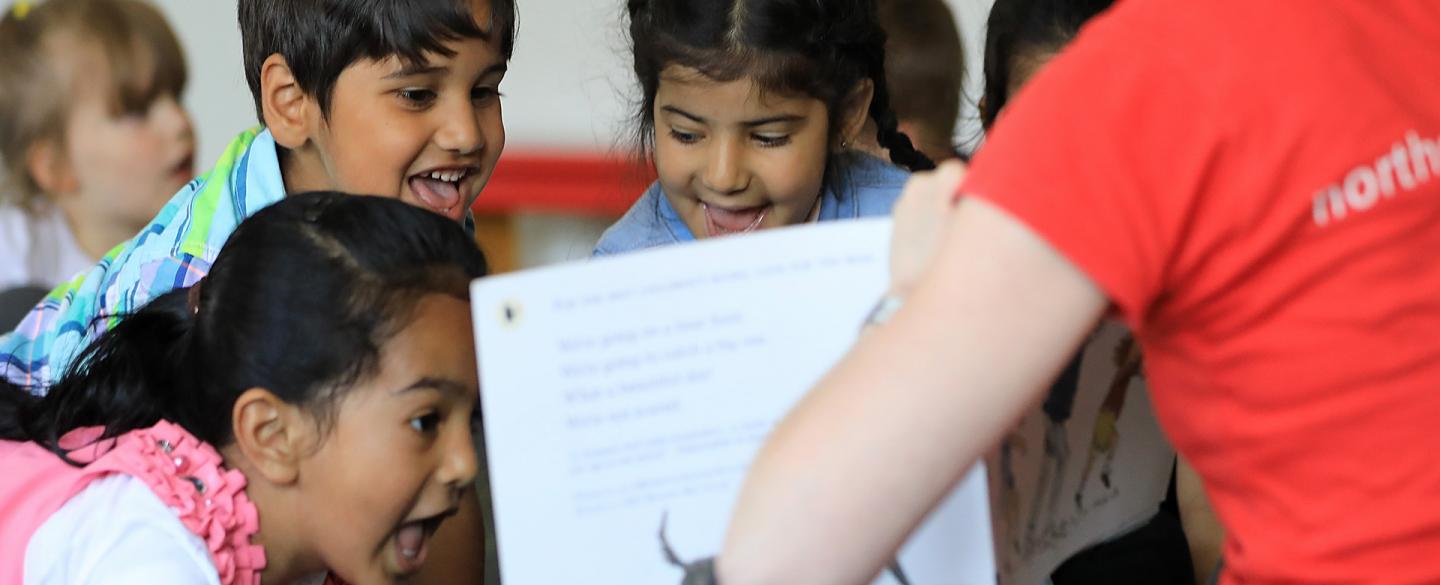 School childern smiling looking at book in classroom environment