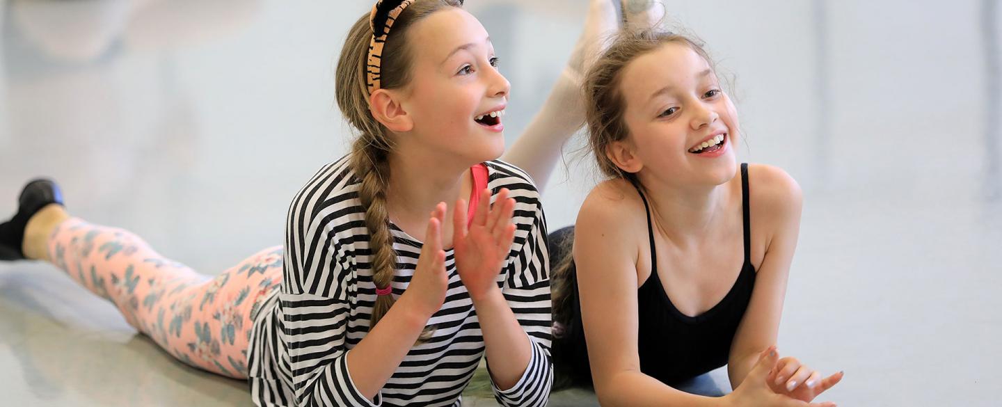 Two girls sat on the floor smiling