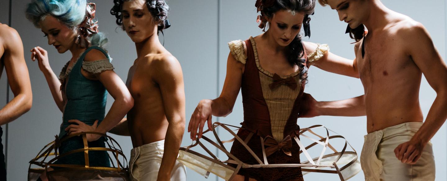 four dancers in costumes prepare to be photographed