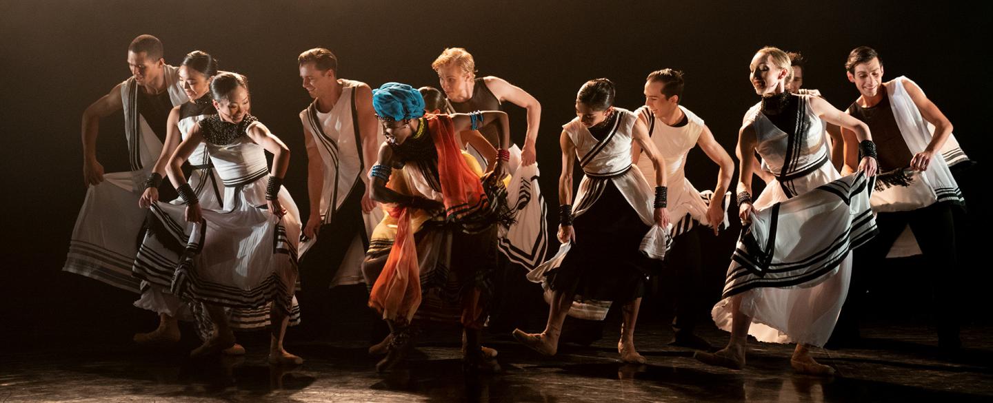 A group of dancers in costume holding the skirts of their dresses