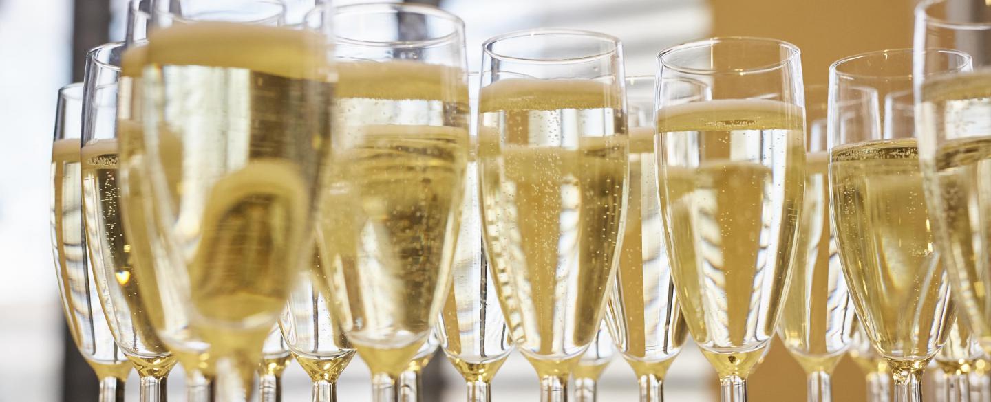Champagne flutes filled with drink on a table top. 