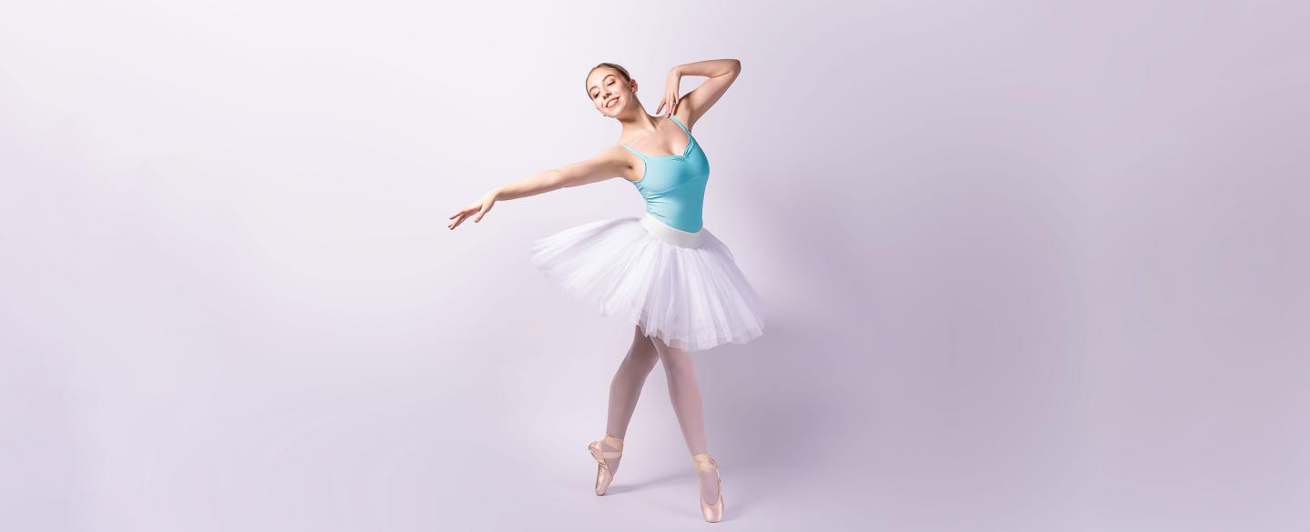 Female dancer in a blue leotard and white tutu on pointe