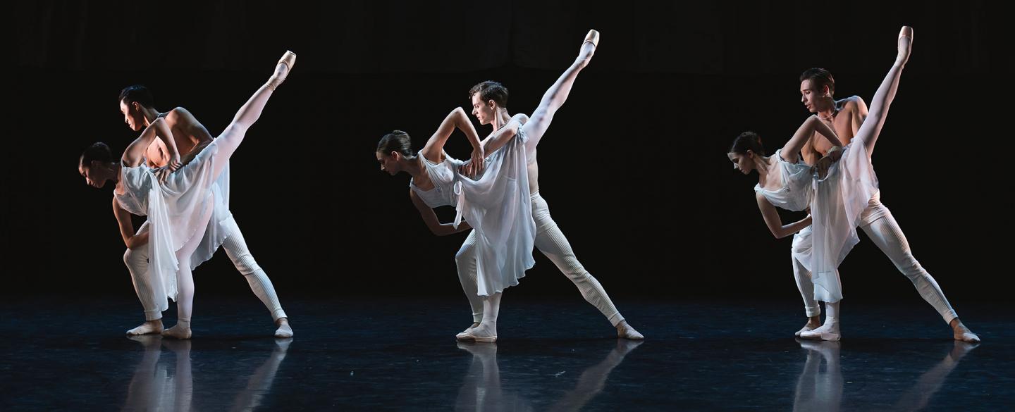 Three couples, each wearing white, a male holds steady a female who is leaning forward on one foot while the other leg is extended in the air behind her