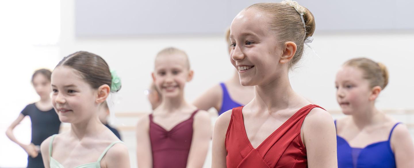 Class of young dance students with their hair tied in buns smiling
