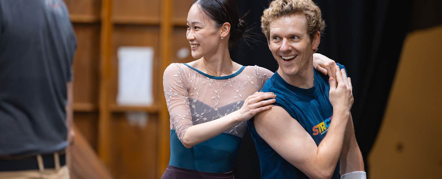 Two dancer in rehearsal smiling at something happening beyond the frame