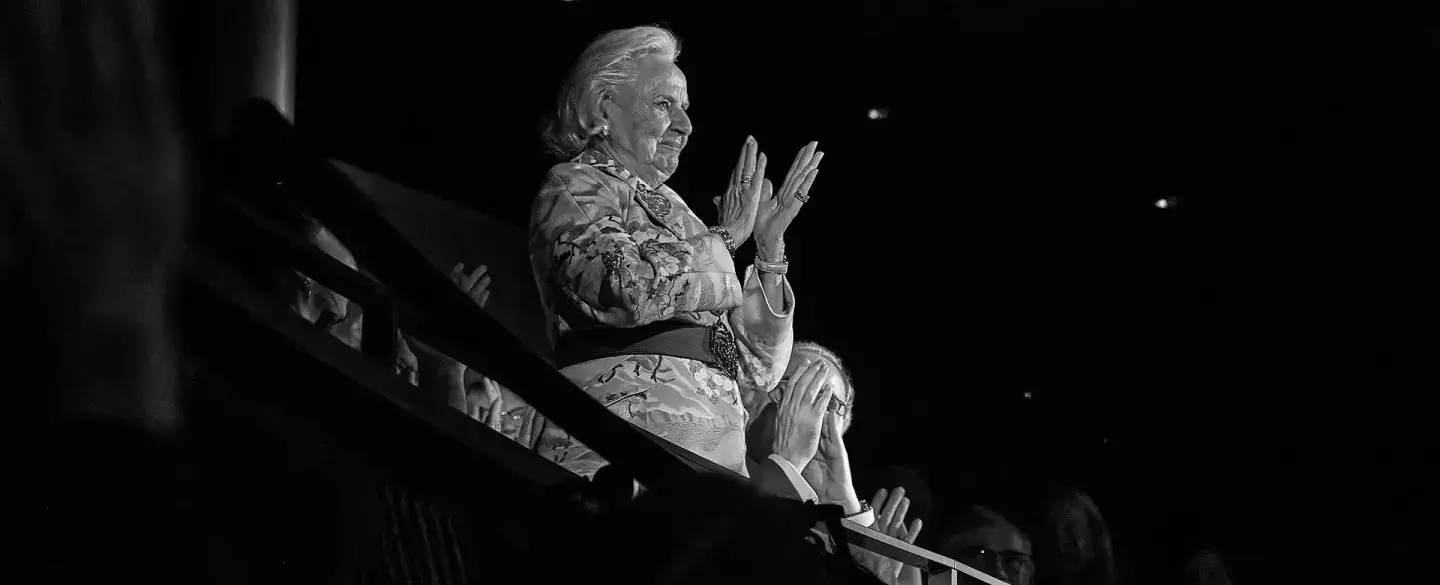 Distinguished woman standing, clapping on a theatre circle