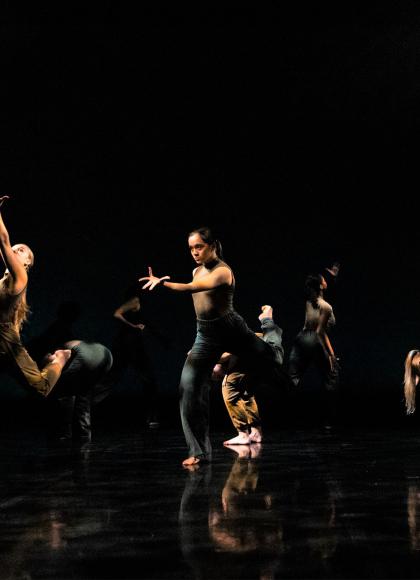 Group of dancers on stage performing against a black background