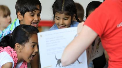 School childern smiling looking at book in classroom environment